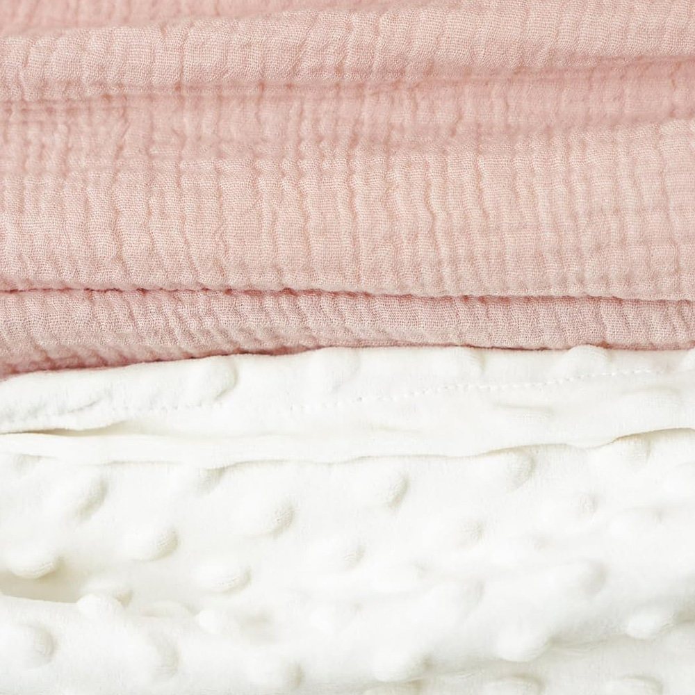 Baby girl lying on a large breathable muslin minky dot sensory blanket